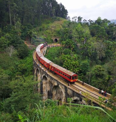 Train crossing a stone viaduct through green hills, 24Trains streaming service