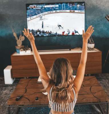 Woman cheering in front of a TV showing ice hockey, sports streaming and piracy