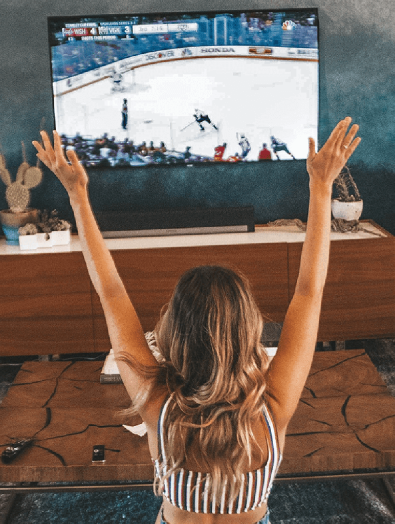 Fan cheering in front of a TV showing ice hockey, viewer satisfaction