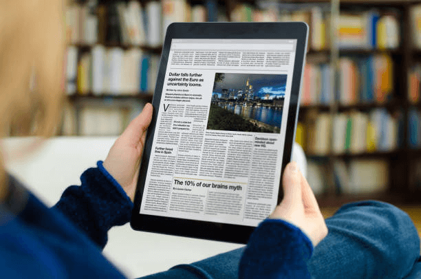 Person reading a digital newspaper on a tablet, about content monetization for publishers
