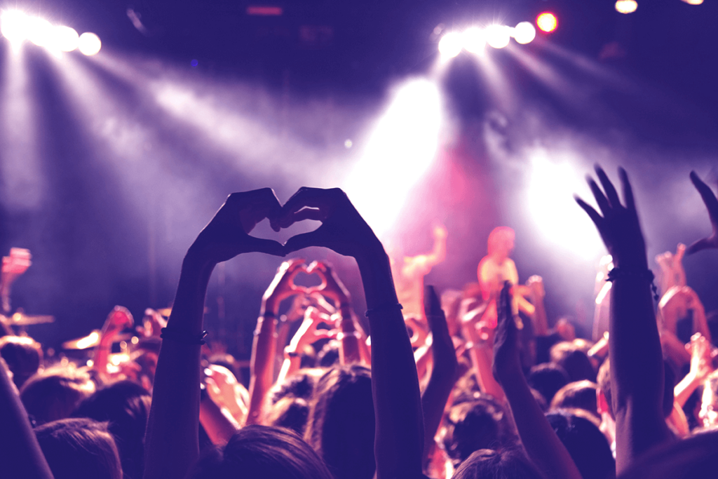 Concert audience making heart shapes with their hands at a live music event