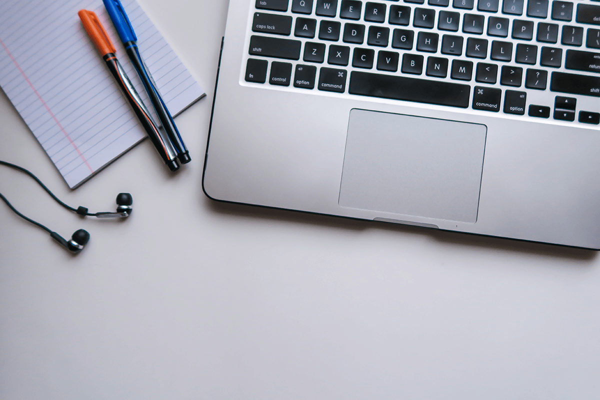Laptop, notebook and pens on a desk, illustrating video for e-learning