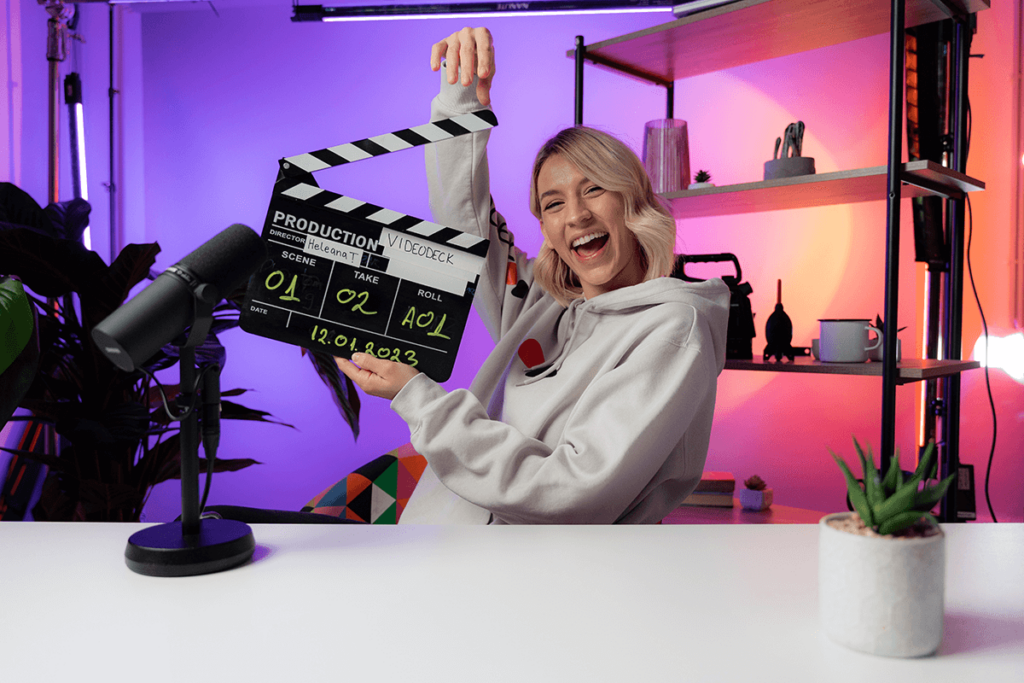 Woman holding a clapperboard in a colourful studio