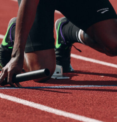 Sprinter in starting blocks on a track, cover for winning sports marketing strategy article