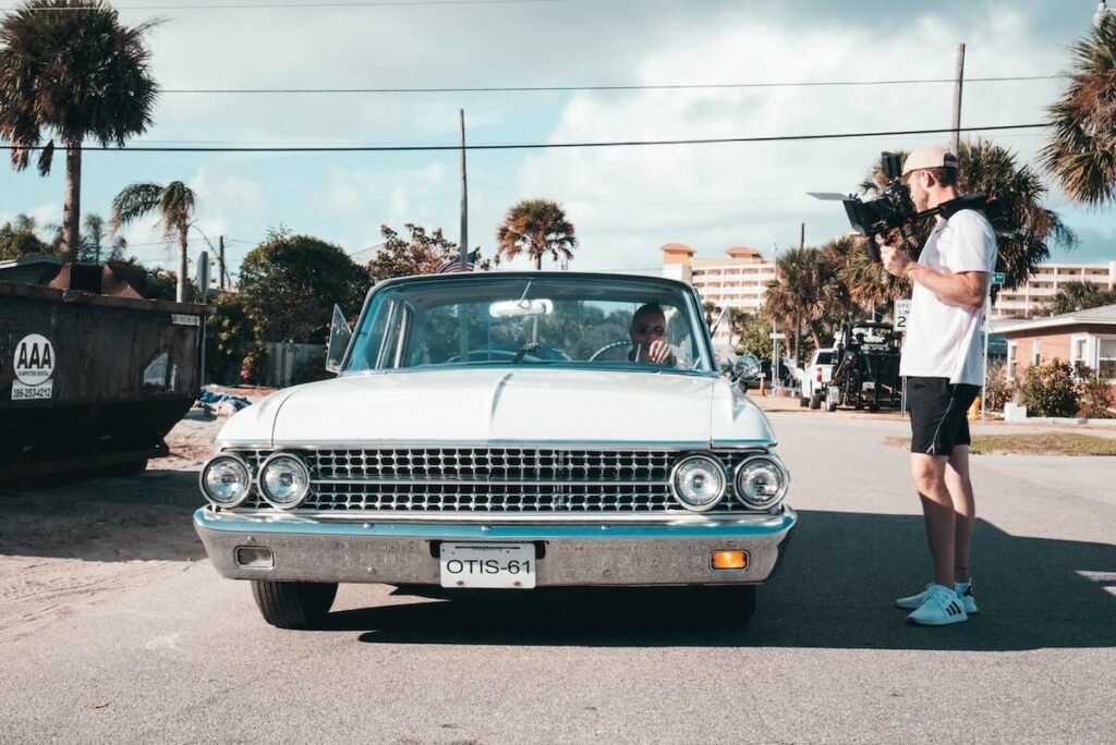 Videographer filming a classic car for a marketing video