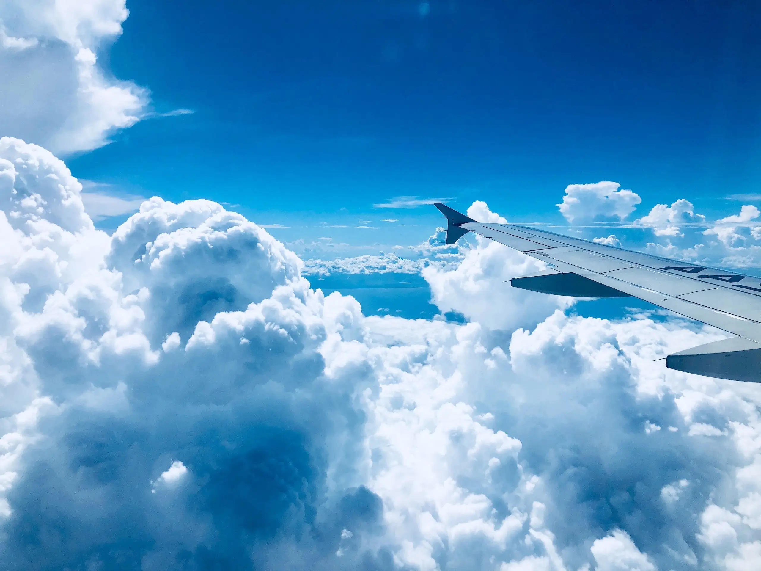 Airplane wing above white clouds